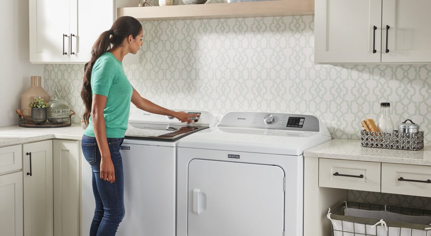 A person selecting a wash cycle on a Maytag® top load washer in a modern laundry room A person selecting a wash cycle on a Maytag® top load washer in a modern laundry room