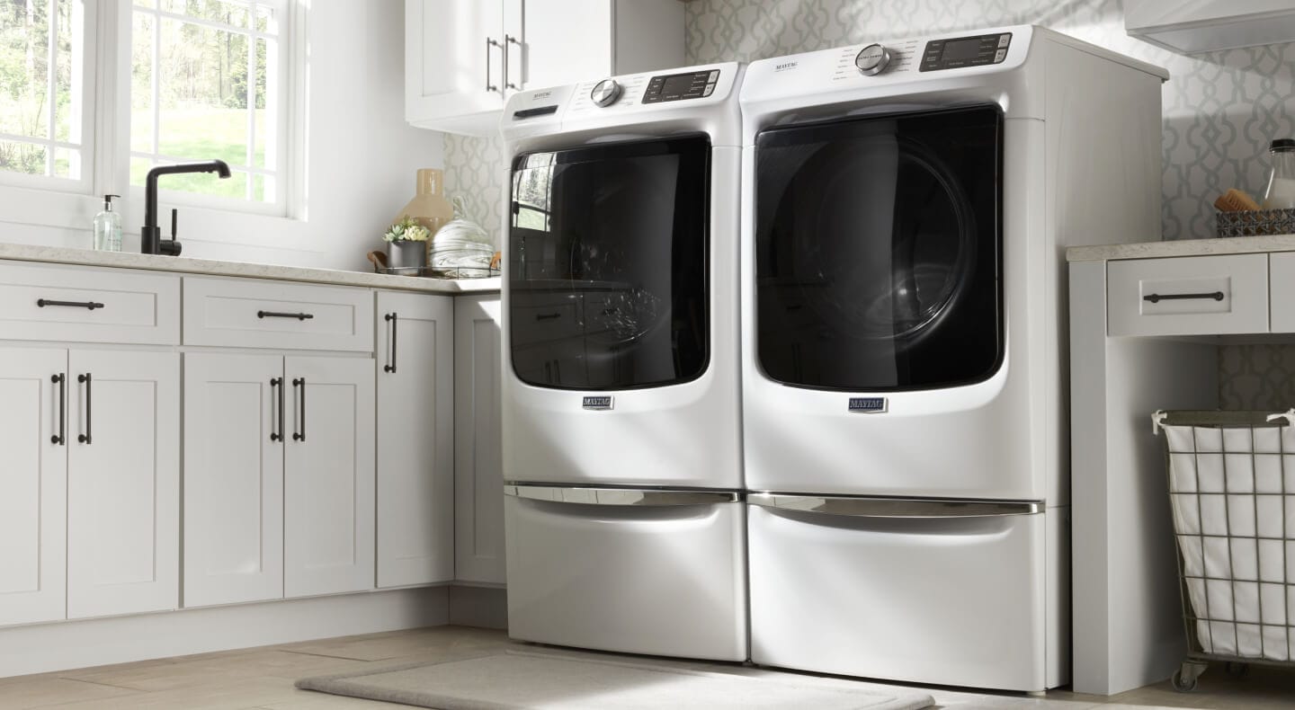 A Maytag® side-by-side top load washer and dryer in a modern laundry room A Maytag® side-by-side top load washer and dryer in a modern laundry room