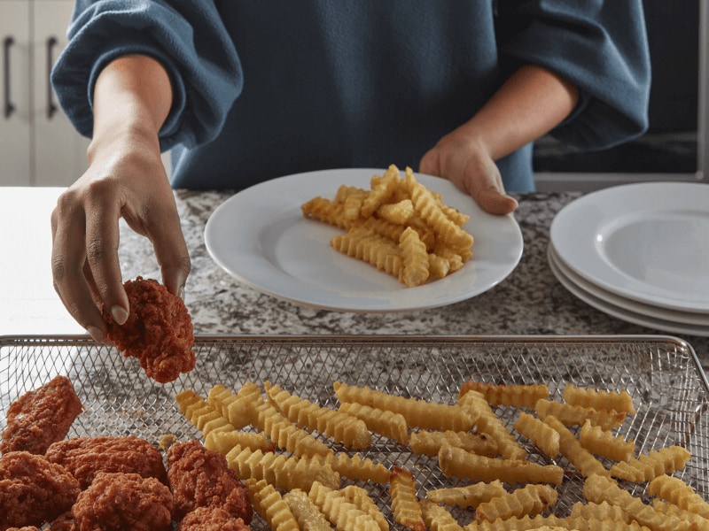Person removing food from air fryer basket
