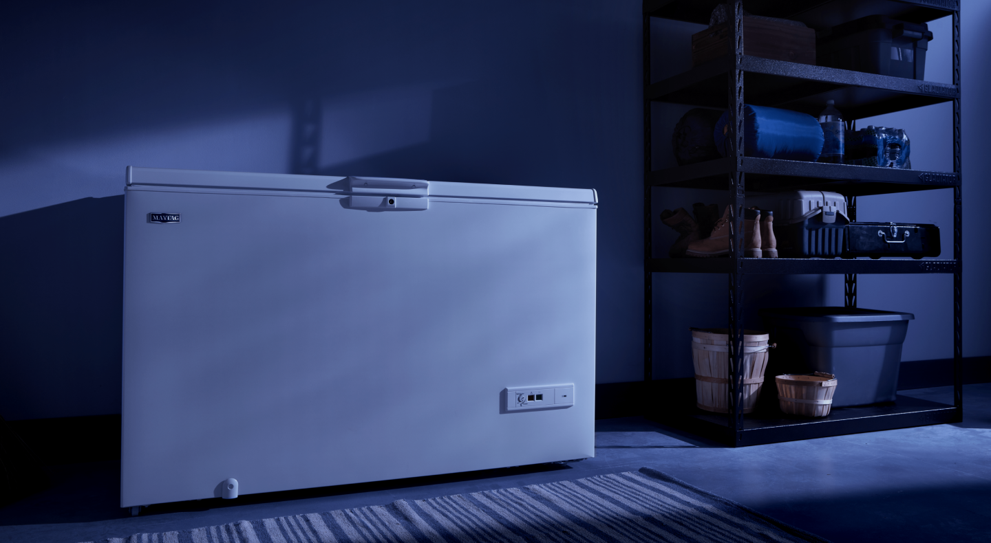 A white Maytag® chest freezer in a dark room A white Maytag® chest freezer in a dark room