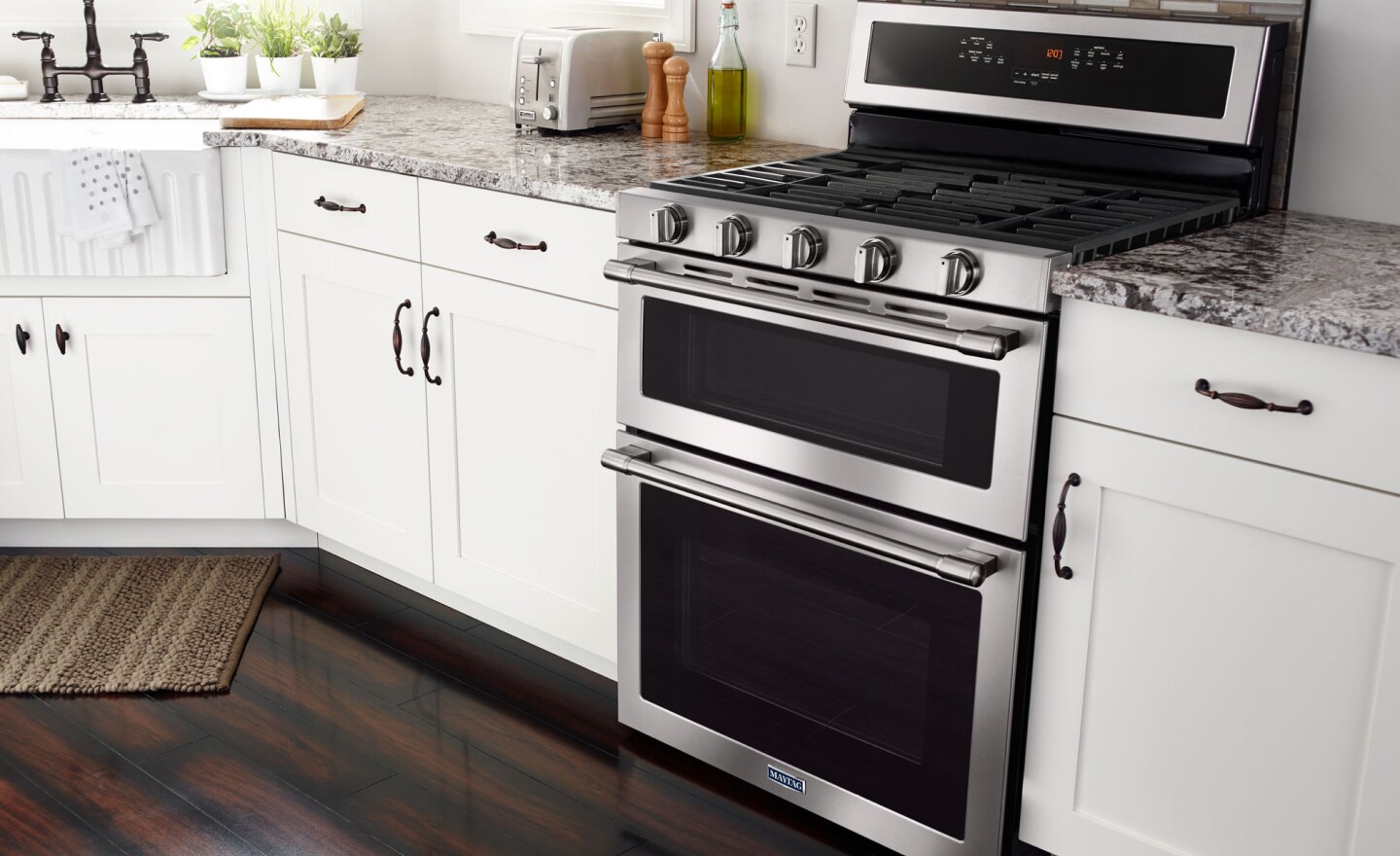 Stainless steel Maytag® gas range in kitchen between countertops and white cupboards Stainless steel Maytag® gas range in kitchen between countertops and white cupboards