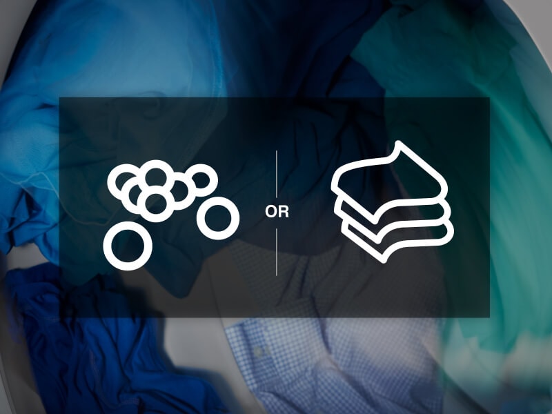 Dryer balls vs sheets icon overlaying clothes tumbling in a dryer Dryer balls vs sheets icon overlaying clothes tumbling in a dryer