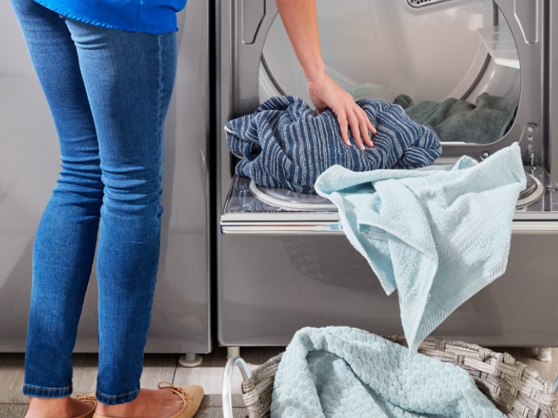 Person unloading a dryer into a basket Person unloading a dryer into a basket