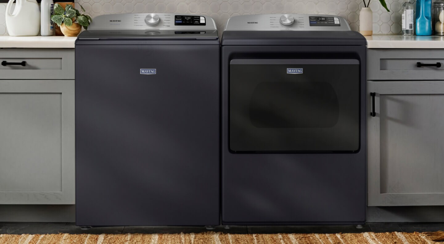 A side-by-side gray washer and dryer set into light gray cabinetry