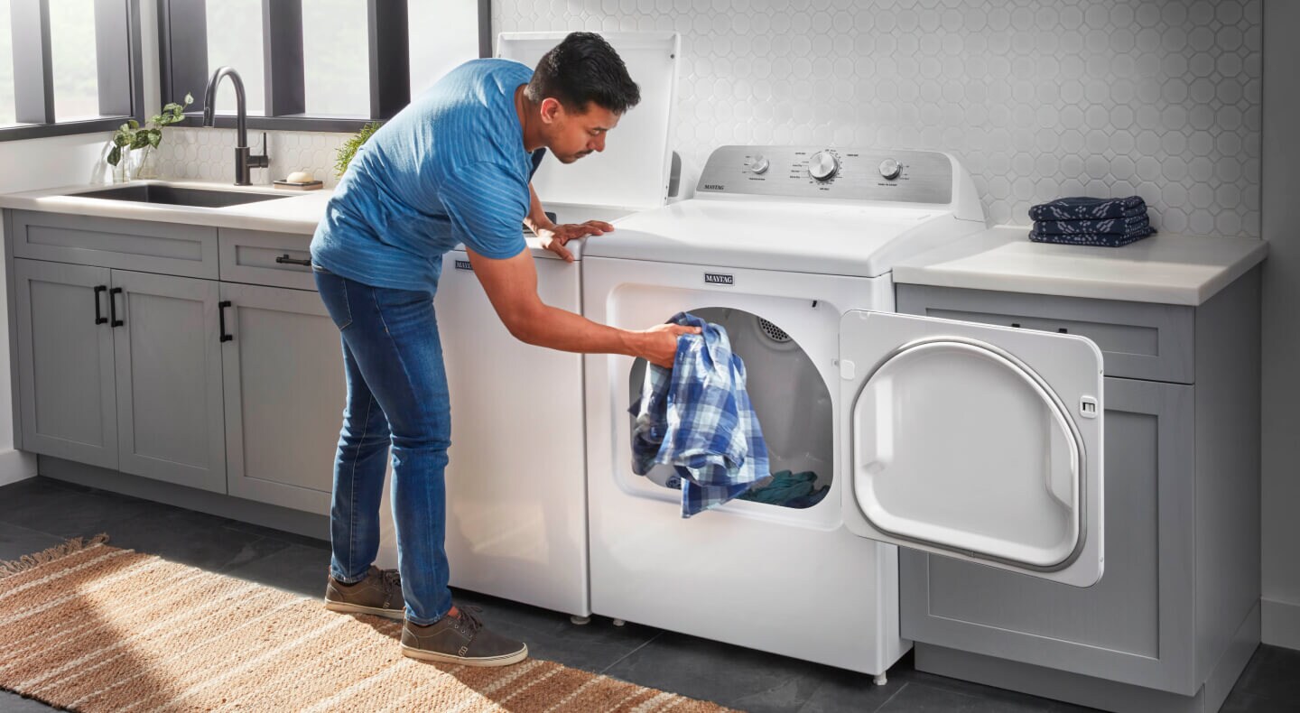 A person putting a shirt in a dryer