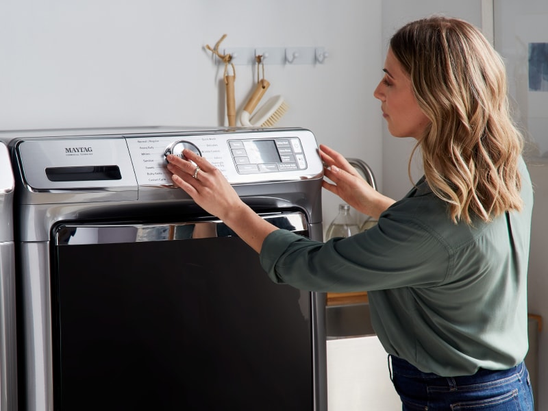 A woman setting a laundry cycle on a Maytag® washing machine A woman setting a laundry cycle on a Maytag® washing machine