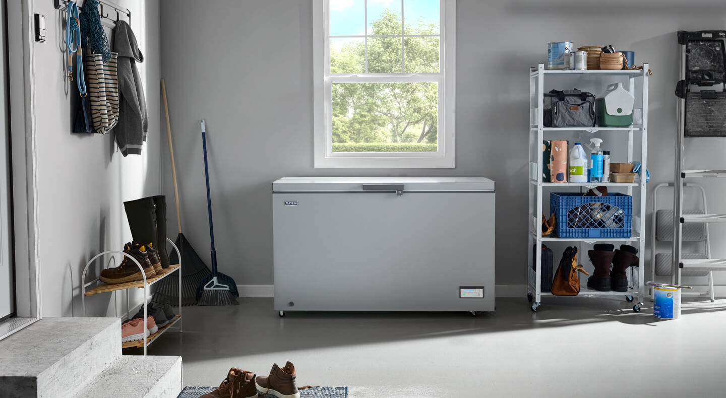 A white Maytag® chest freezer under a window in a garage