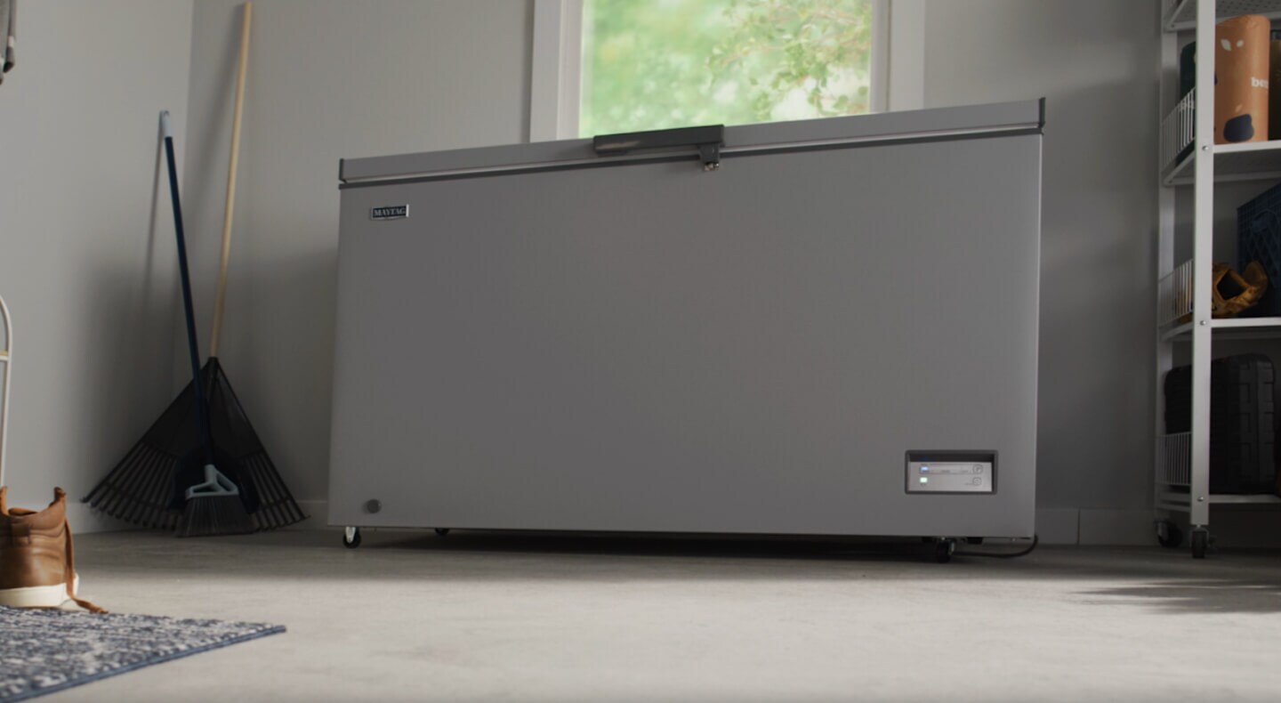 A grey Maytag® chest freezer in a garage