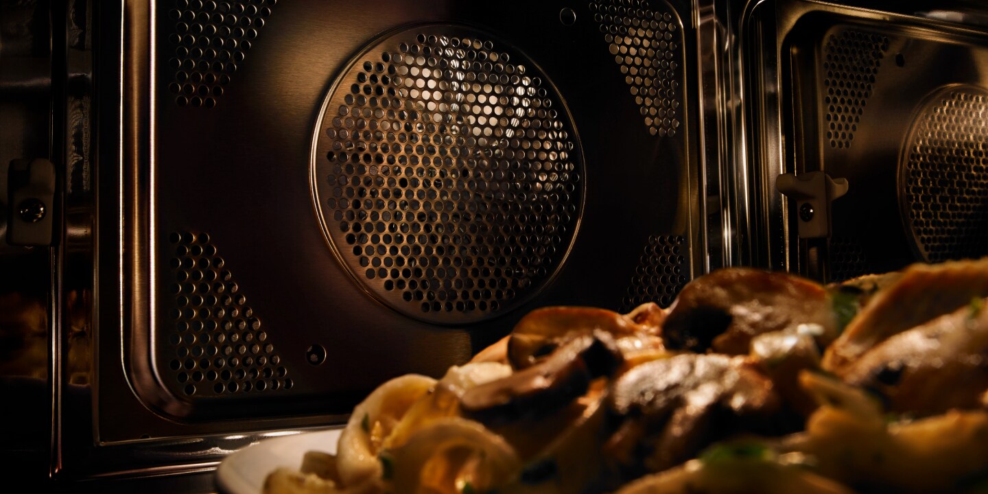 A close-up of a Maytag® convection microwave interior with a plate of pasta A close-up of a Maytag® convection microwave interior with a plate of pasta