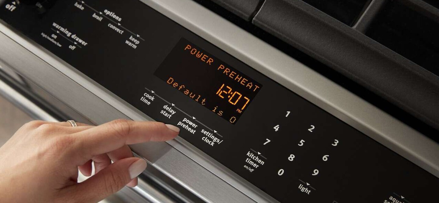 Hand selecting option on a range's glass console Hand selecting option on a range's glass console