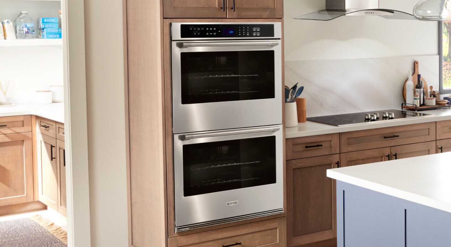 A double wall oven in a kitchen with wood cabinets and white countertops