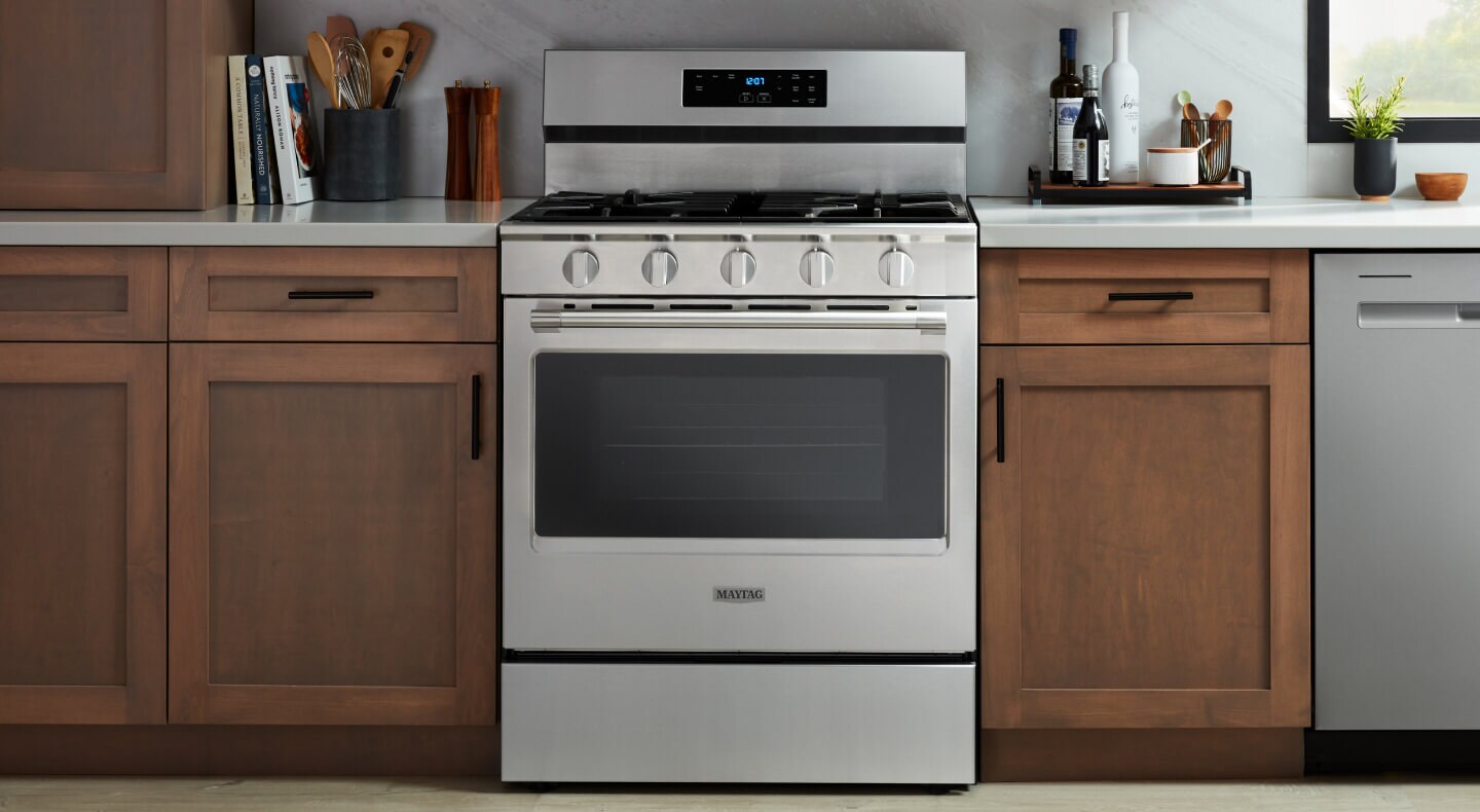 A stainless steel single oven in a kitchen with wood cabinets and white countertops
