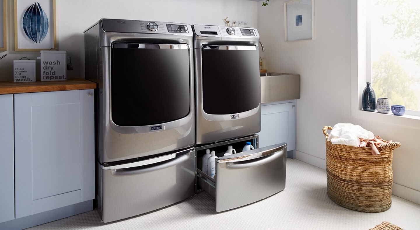 Maytag® front load laundry pair on pedestals with one pedestal drawer open Maytag® front load laundry pair on pedestals with one pedestal drawer open