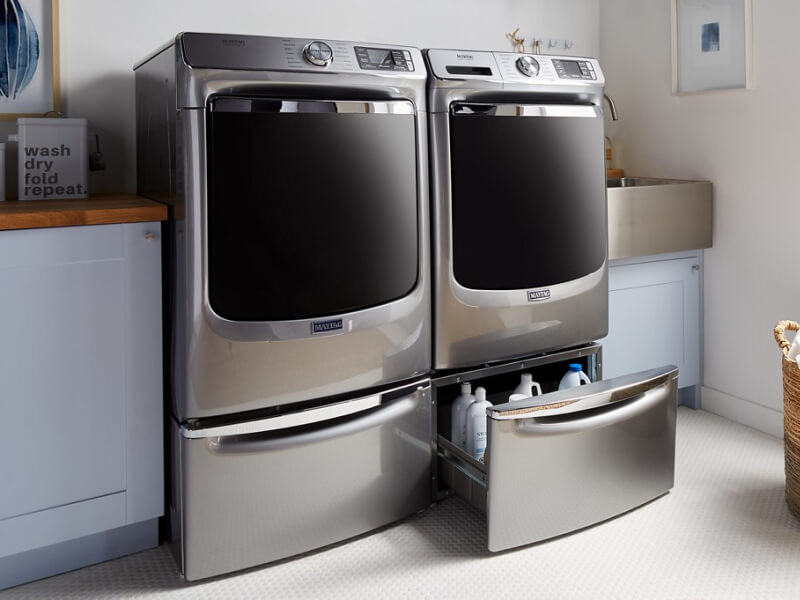 Maytag® front load laundry pair on pedestals with one pedestal drawer open Maytag® front load laundry pair on pedestals with one pedestal drawer open