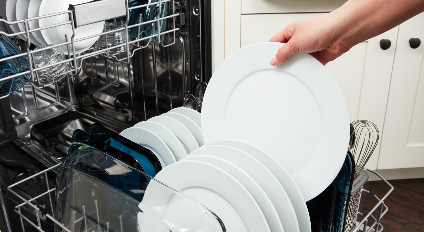 A person loading dishes into a Maytag® dishwasher. A person loading dishes into a Maytag® dishwasher.