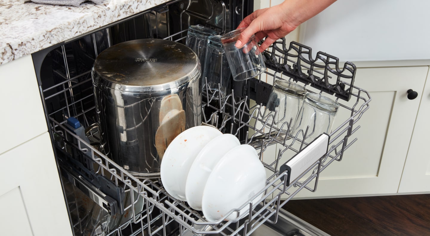 A person loading dishes into a Maytag® dishwasher. A person loading dishes into a Maytag® dishwasher.