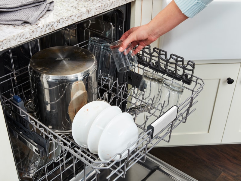 A person loading dishes into a Maytag® dishwasher. A person loading dishes into a Maytag® dishwasher.