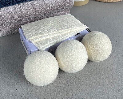 Wool dryer balls next to dryer sheets
