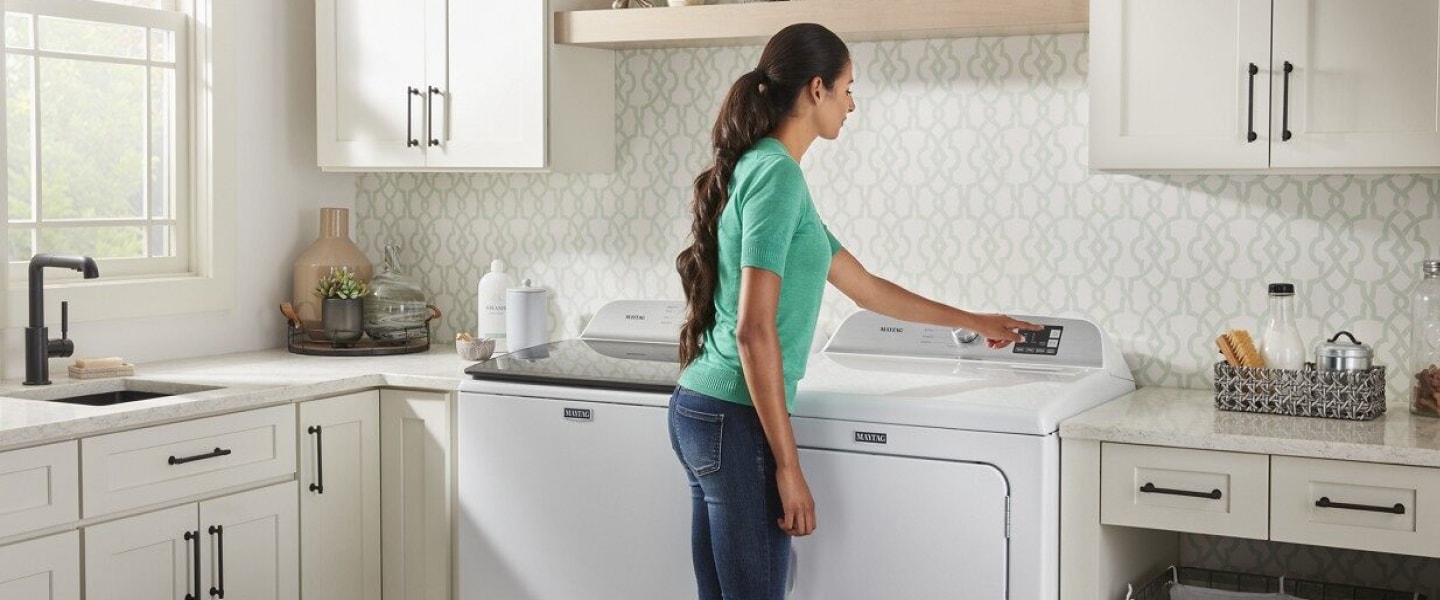 Person selecting option on a dryer in a white laundry room Person selecting option on a dryer in a white laundry room
