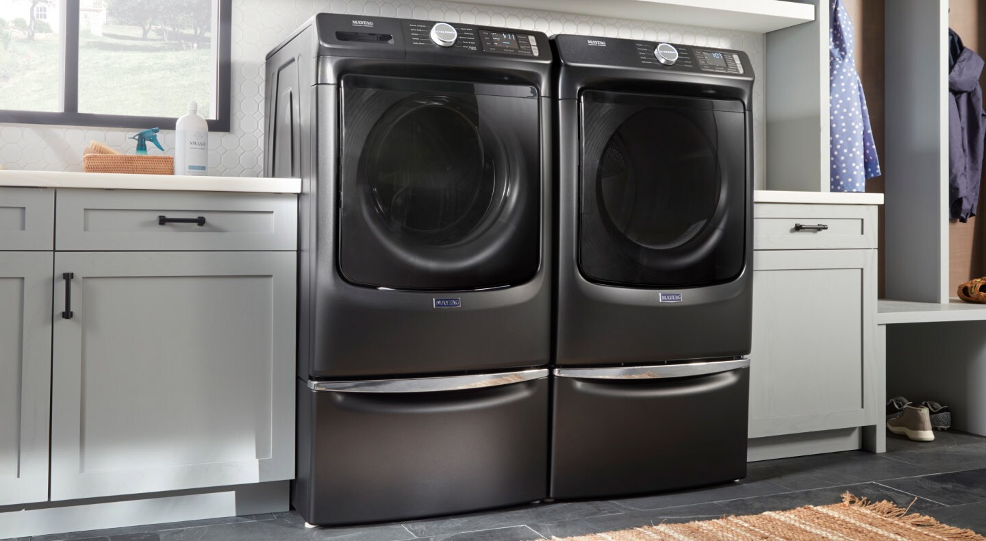 Black Maytag® front-load washer and dryer pair on pedestals