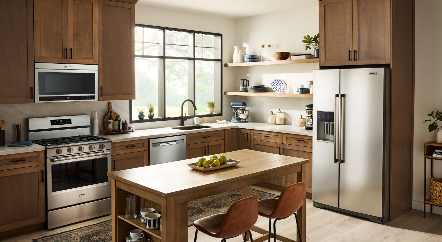 A kitchen with wood-colored cabinets and an island as well as stainless steel appliances