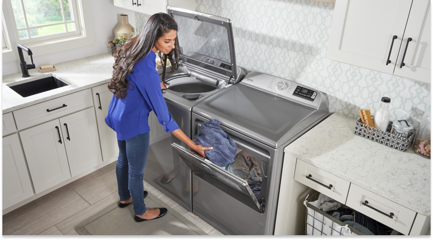 Person transferring wet clothes from a top-load washer to the dryer Person transferring wet clothes from a top-load washer to the dryer