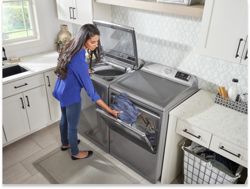 Person transferring wet clothes from a top-load washer to the dryer Person transferring wet clothes from a top-load washer to the dryer