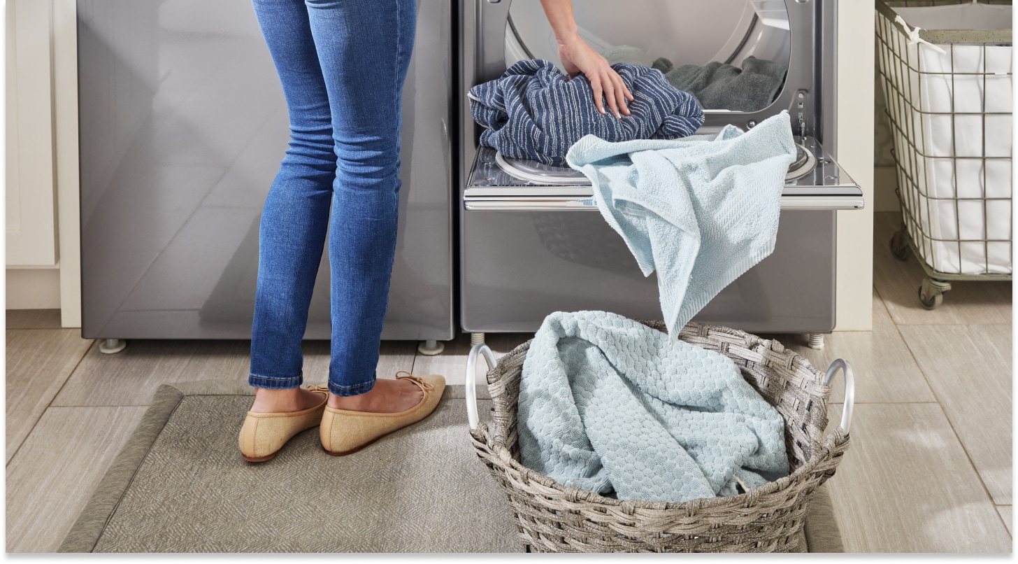 Person unloading clothes from the dryer into a laundry basket Person unloading clothes from the dryer into a laundry basket