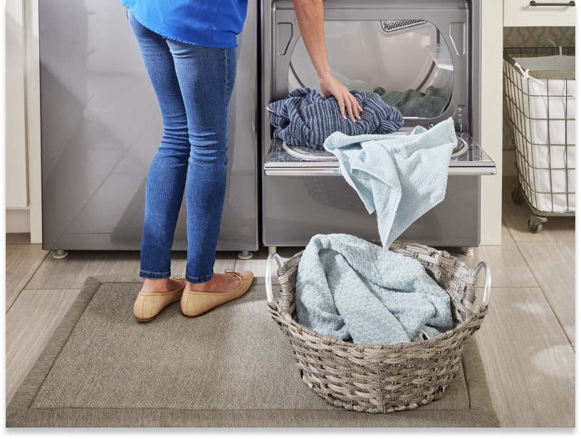 Person unloading clothes from the dryer into a laundry basket Person unloading clothes from the dryer into a laundry basket