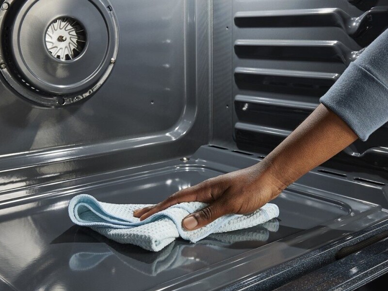 Hand wiping down the inside of an oven with a dry cloth Hand wiping down the inside of an oven with a dry cloth