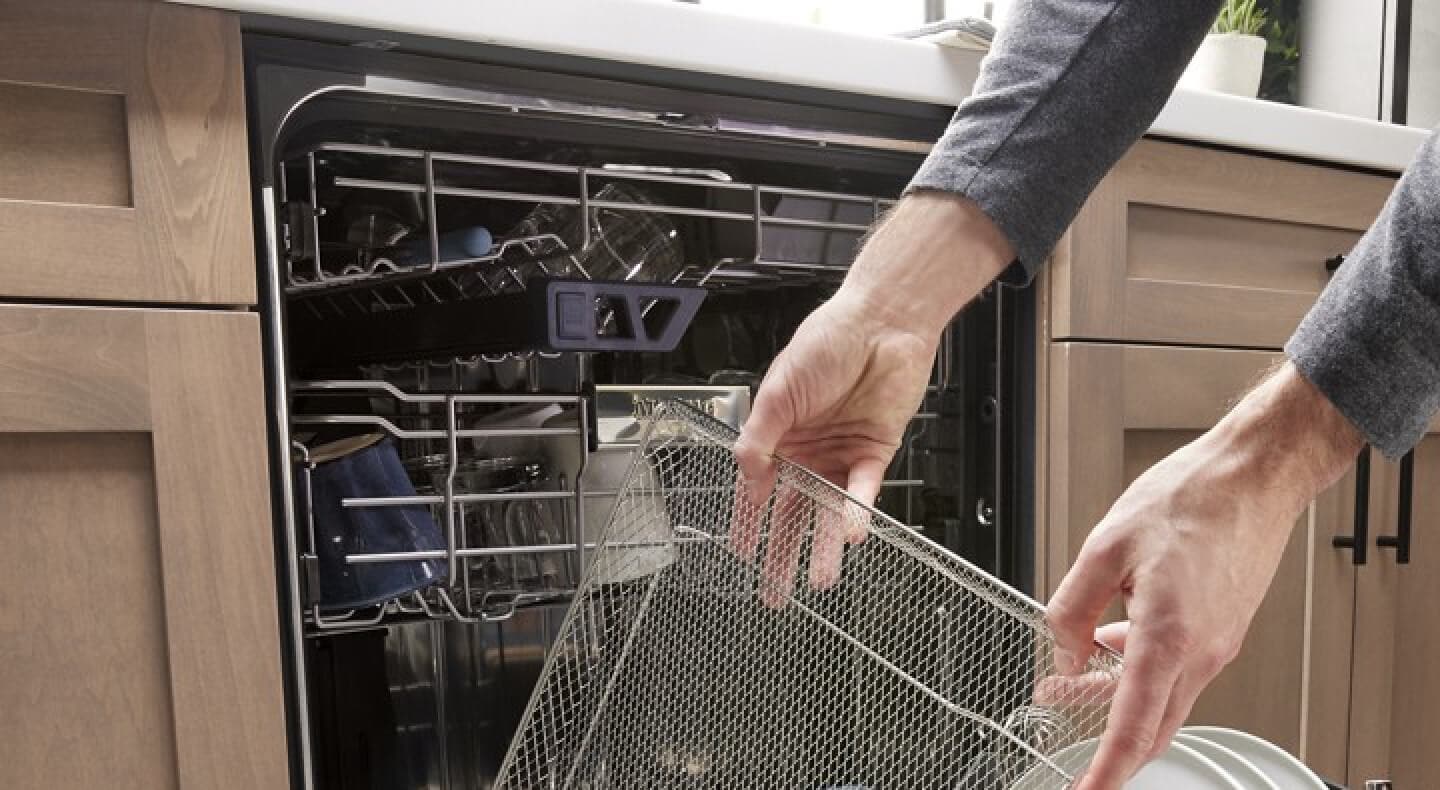 A person pulling an air fry basket out of a Maytag® dishwasher A person pulling an air fry basket out of a Maytag® dishwasher