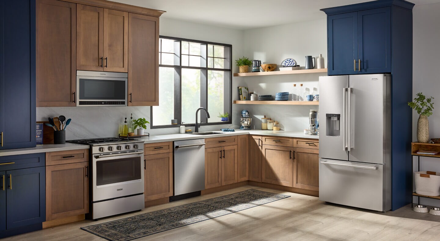 A bright kitchen with blue and wood cabinets and stainless steel appliances