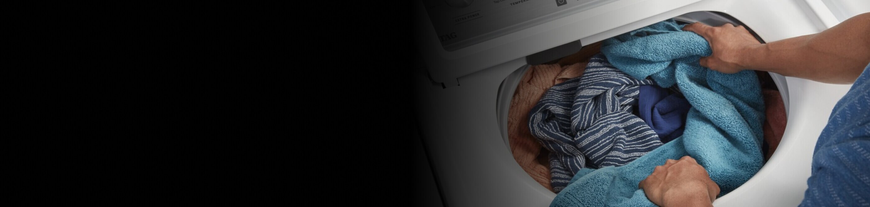 Person adding laundry to a washing machine