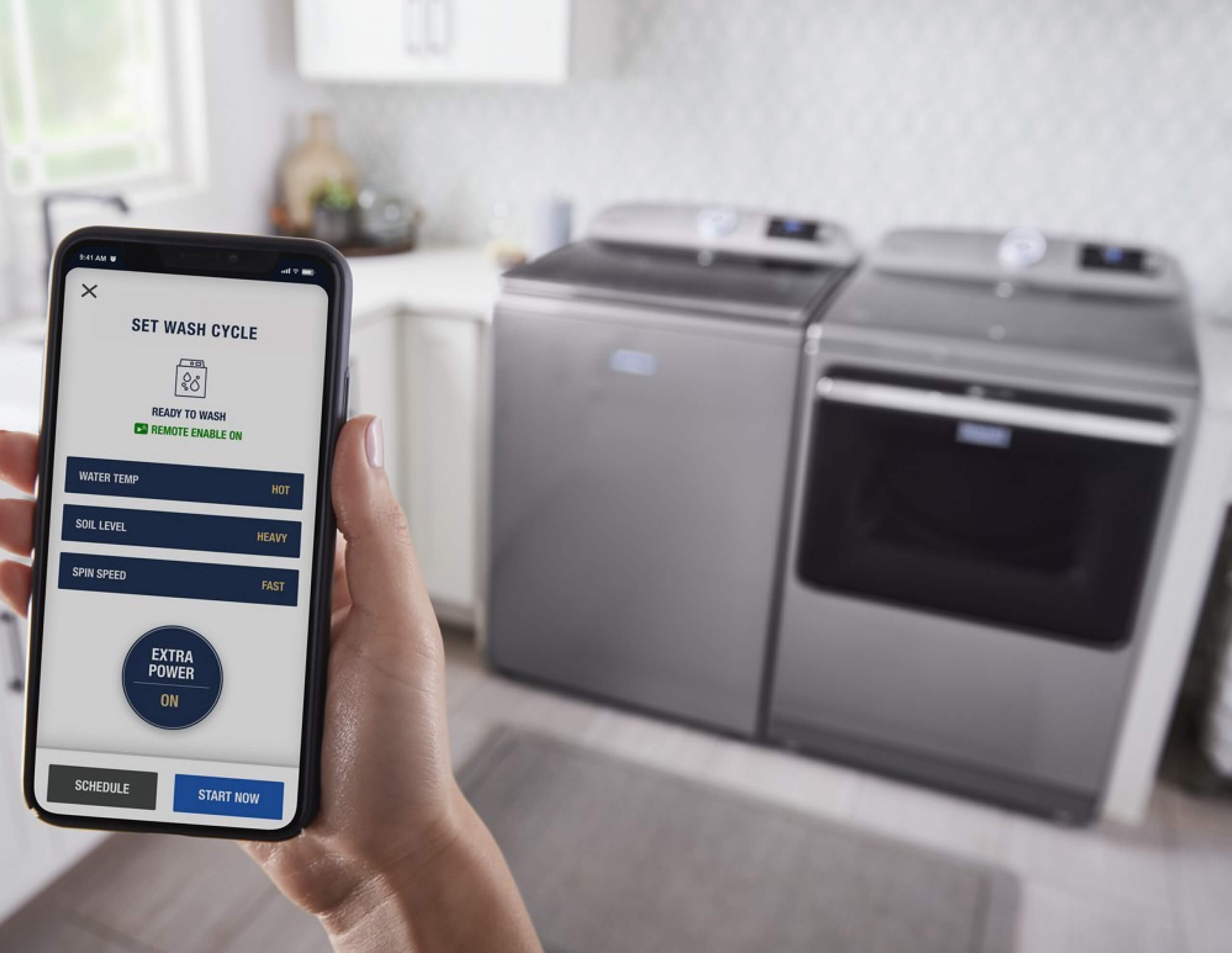 A person’s hand holding their phone, which is being used to control their washer and dryer