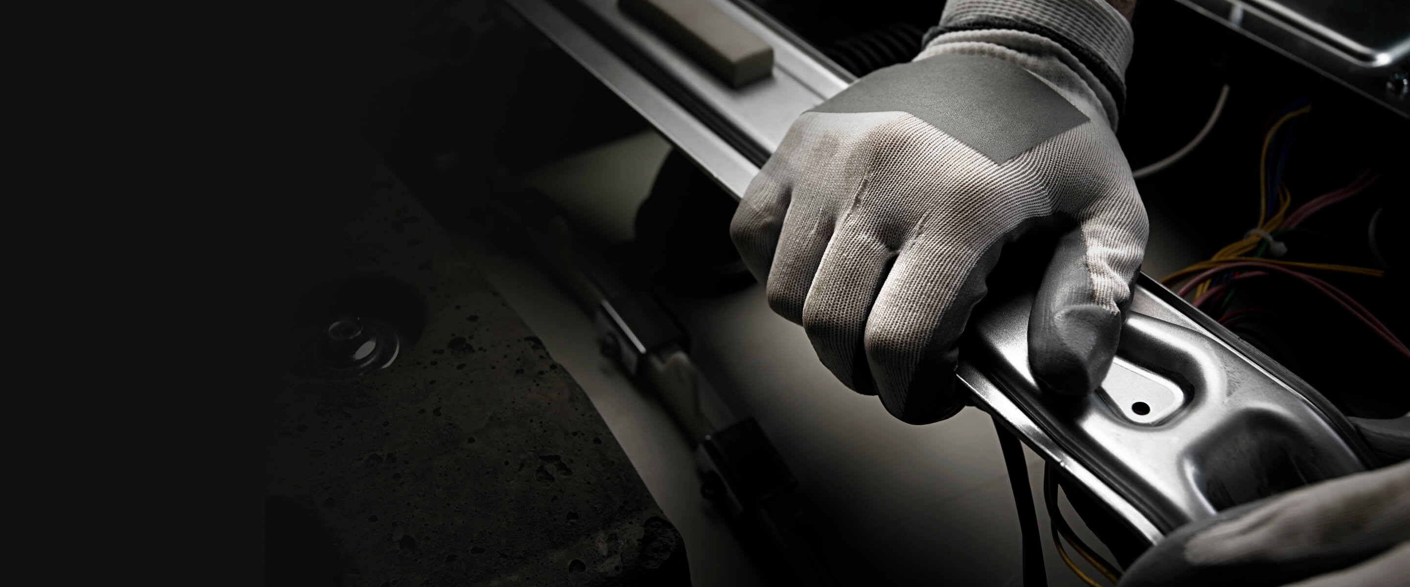 Hand with work glove moving a piece of stainless steel