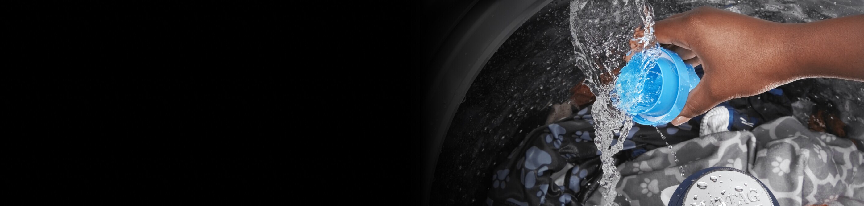 Someone rinsing a detergent cap in the water stream of their washer