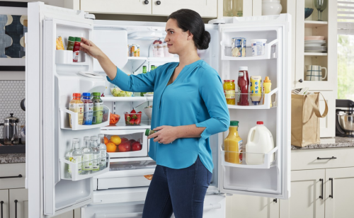 Person placing food in side door of refrigerator