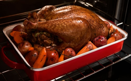 A roasted turkey and vegetables in a baking dish
