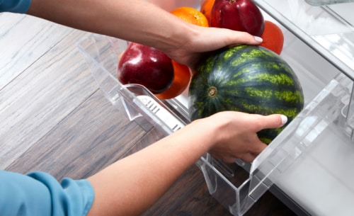 Watermelon being placed into a crisper drawer
