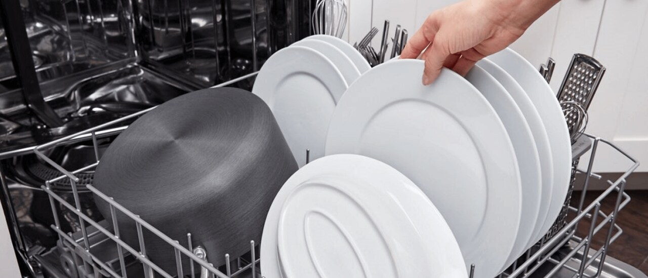 Hand unloading a clean, white dish Hand unloading a clean, white dish