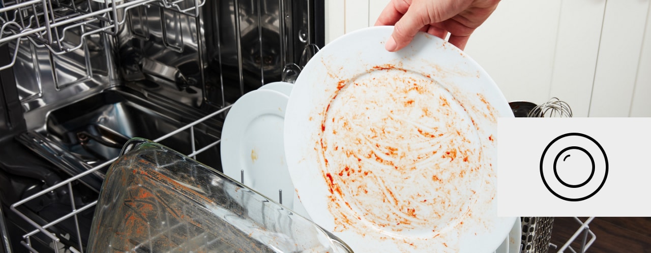 Hand placing dirty white plate into a dishwasher