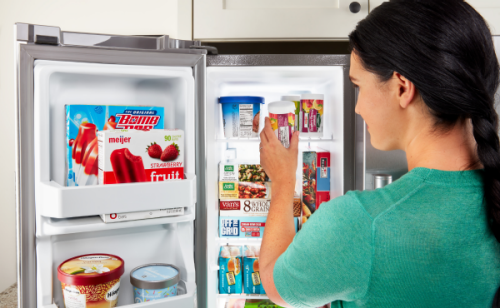 Person placing frozen goods into refrigerator freezer