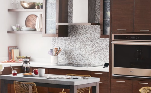 Range hood above an electric stovetop in front of a tile backsplash