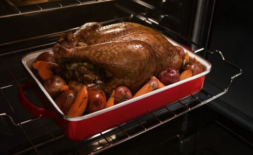 Turkey in roasting pan with carrots and potatoes