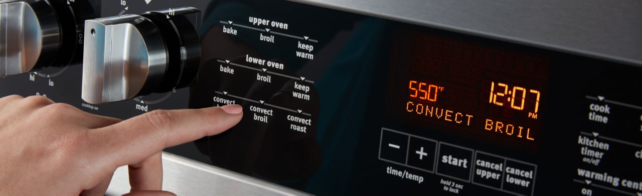 Hand selecting a broil setting on an oven console Hand selecting a broil setting on an oven console