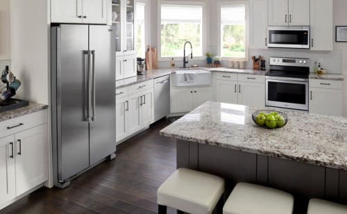 Stainless steel side-by-side refrigerator in white cabinetry