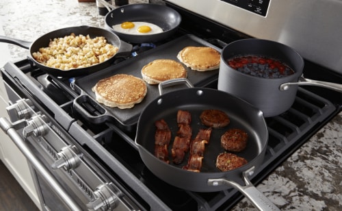 Pans cooking breakfast foods on a Maytag® cooktop