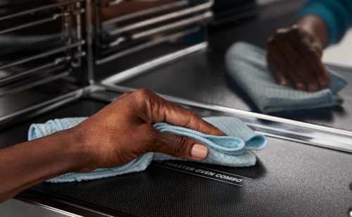 Person cleaning the inside of a Maytag® microwave