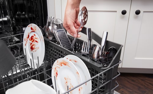 Hand loading silverware into a dishwasher