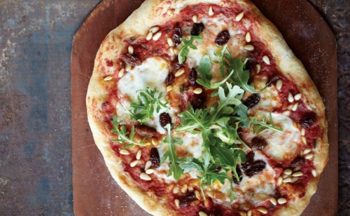A homemade pizza with raisins and parsley on top